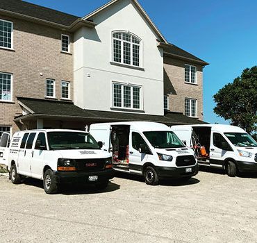 Fleet of Einwechter Plumbing & Heating service vans parked outside a commercial building.